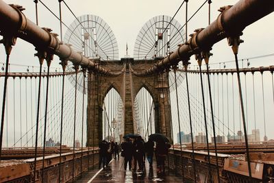 People on bridge against sky in city