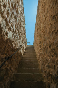 Staircase made of stone bricks going up towards a thick wall around the town in avila, spain.