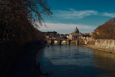 Arch bridge over river against buildings in city