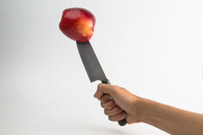 Close-up of hand holding strawberry against white background