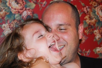 Close-up of father with cheerful daughter by floral pattern wall