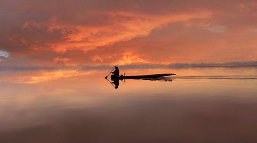 Silhouette person in boat against sky during sunset