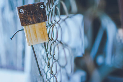 Close-up of figurine hanging on chainlink fence