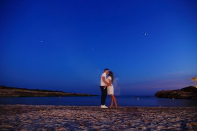 Woman standing on blue sea against sky at night