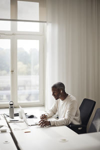 Businessman working on laptop at desk while sitting in office