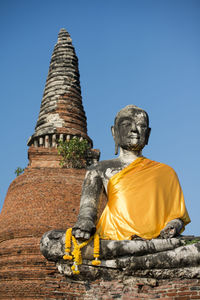 Low angle view of buddha statue at wat mahathat against clear sky