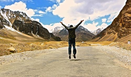 Full length rear view of man walking on mountain against sky