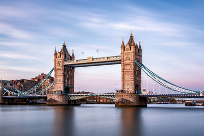 Tower bridge over river against during sunset