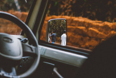 Pov from inside of car through mirror to the people behind