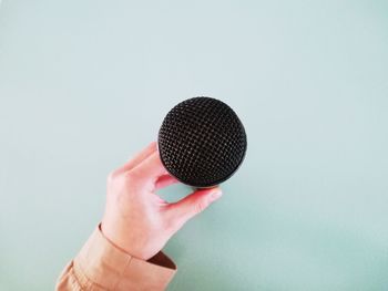 Close-up of hand holding ring against gray background