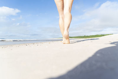 Low section of woman standing at beach