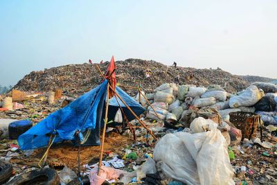 Garbage on rock by sea against clear sky