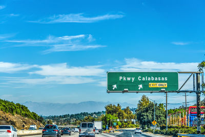 Information sign by road against sky