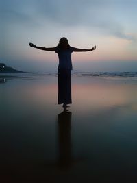 Man standing by sea against sky during sunset