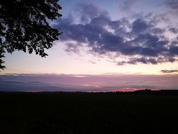 Scenic view of silhouette field against sky at sunset