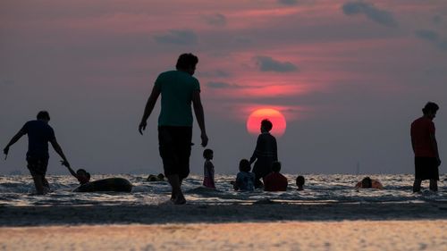 Silhouette people at beach during sunset