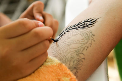 Cropped image of woman tattooing on hand