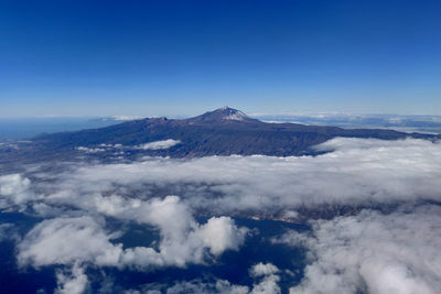 Aerial view of snowcapped mountains against blue sky