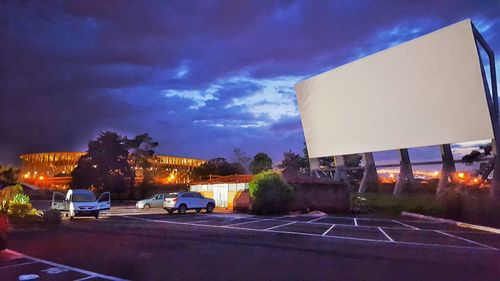 Vehicles on road along buildings at night