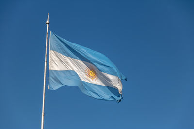 Low angle view of flag against clear blue sky