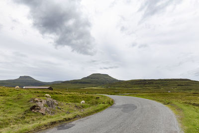 Road amidst green landscape against sky