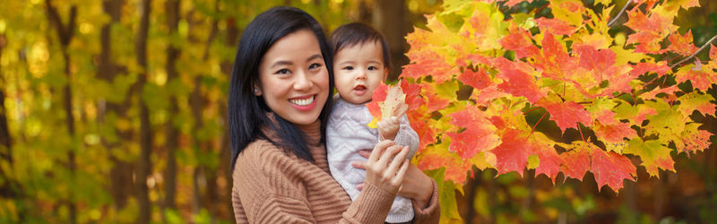 Mother and daughter in park touching autumn leaf at park