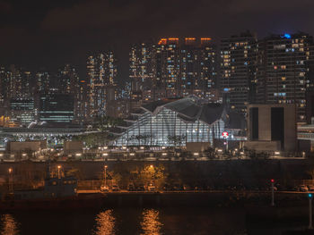 Illuminated city by river at night