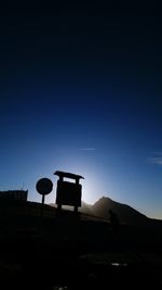 Silhouette of road sign against clear blue sky