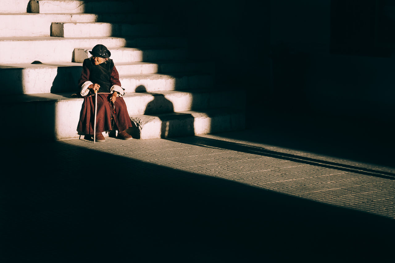 real people, one person, shadow, full length, sitting, women, sunlight, adult, architecture, lifestyles, front view, young women, staircase, casual clothing, built structure, seat, day, indoors, waiting