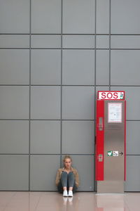 Full length of woman standing by wall