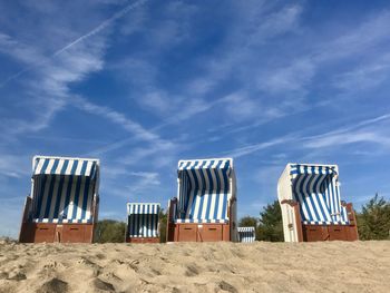 Hooded chairs on beach against blue sky