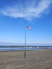 Flag on beach against sky