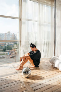 Young man sitting on window