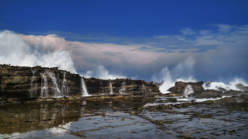 Scenic view of waterfall against sky