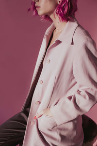 Midsection of woman wearing coat against colored background