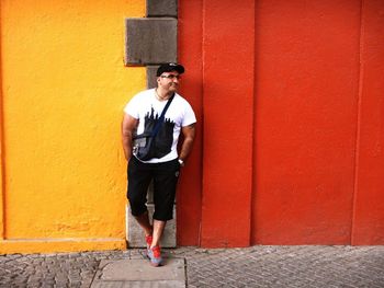 Full length portrait of young man standing against wall