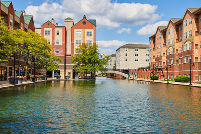 Buildings by river against sky