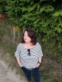 Beautiful young woman standing against plants