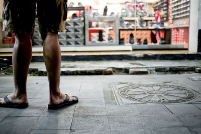 Low section of men standing on shoes front store