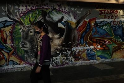 Full length of man standing against graffiti wall
