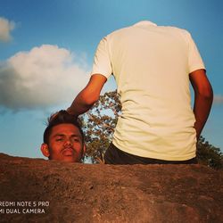 Low angle view of father and daughter against sky