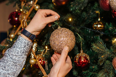 Cropped hand of woman decorating christmas tree