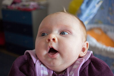 Close-up of cute baby girl looking away at home