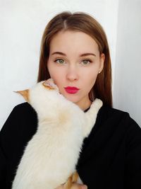 Portrait of woman with cat against wall