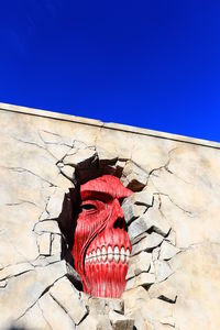 Close-up of red wall against blue sky