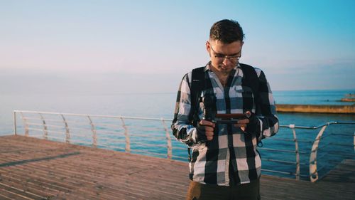 Man standing at sea shore against sky