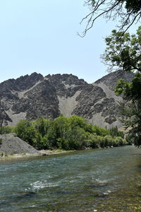 Scenic view of river by mountains against clear sky