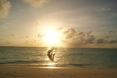 Silhouette person on beach against sky during sunset