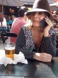 Portrait of young woman drinking glass on table at restaurant