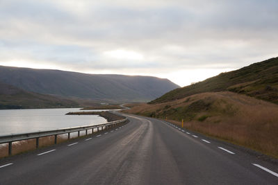 Country road against cloudy sky